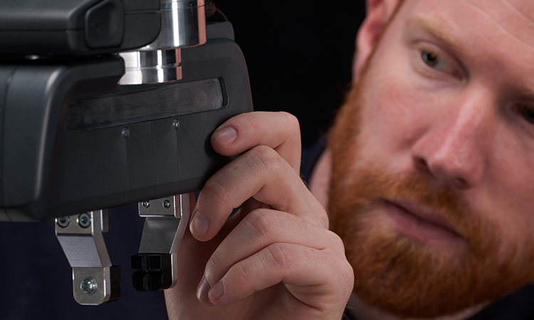 A man sets up Franka Production 3 and holds the gripper in his hands